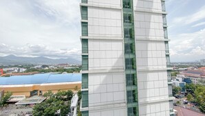 A modern high-rise building with a glass facade and a view of a cityscape and mountains in the background.