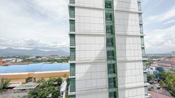 Un moderno edificio de rascacielos con fachada de vidrio y vistas a un paisaje urbano y montañas al fondo.