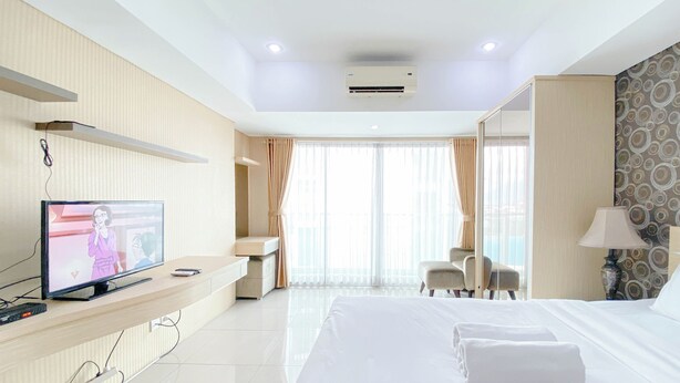 A hotel room with a bed, a TV, a desk, and a chair.