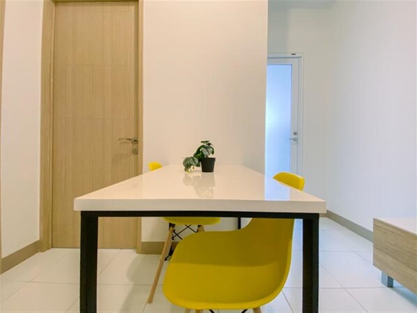 A modern room with a white table, yellow chairs, and a small potted plant.