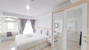 Una camera d'albergo moderna con un letto grande, una scrivania, una sedia, una televisione e un armadio.