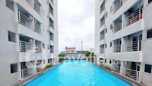 Una piscina circondata da edifici a più piani con balconi e condizionatori.