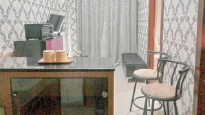 A small room with a desk, two chairs, a television, and a curtain. - The Urban 2BR at Vida View Makassar Apartment (Makassar)