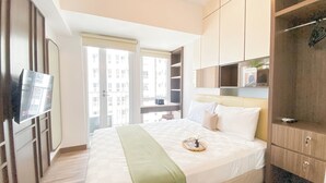 Une chambre d’hôtel avec un lit, une table de chevet et une fenêtre donnant sur des immeubles.
