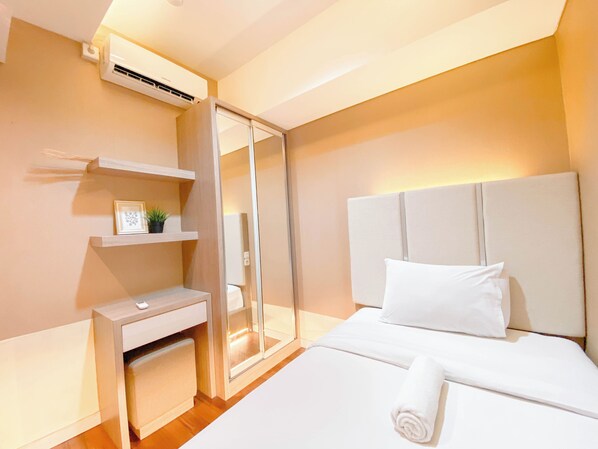 Una habitación de hotel moderna con una cama, mesita de noche y un escritorio empotrado con una silla.