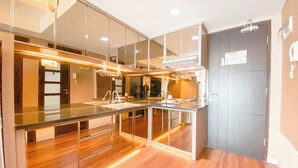 A modern kitchen with a central island, stainless steel appliances, and a wooden floor. - The Bohemian 2BR at Tamansari La Grande Apartment (Bandung)