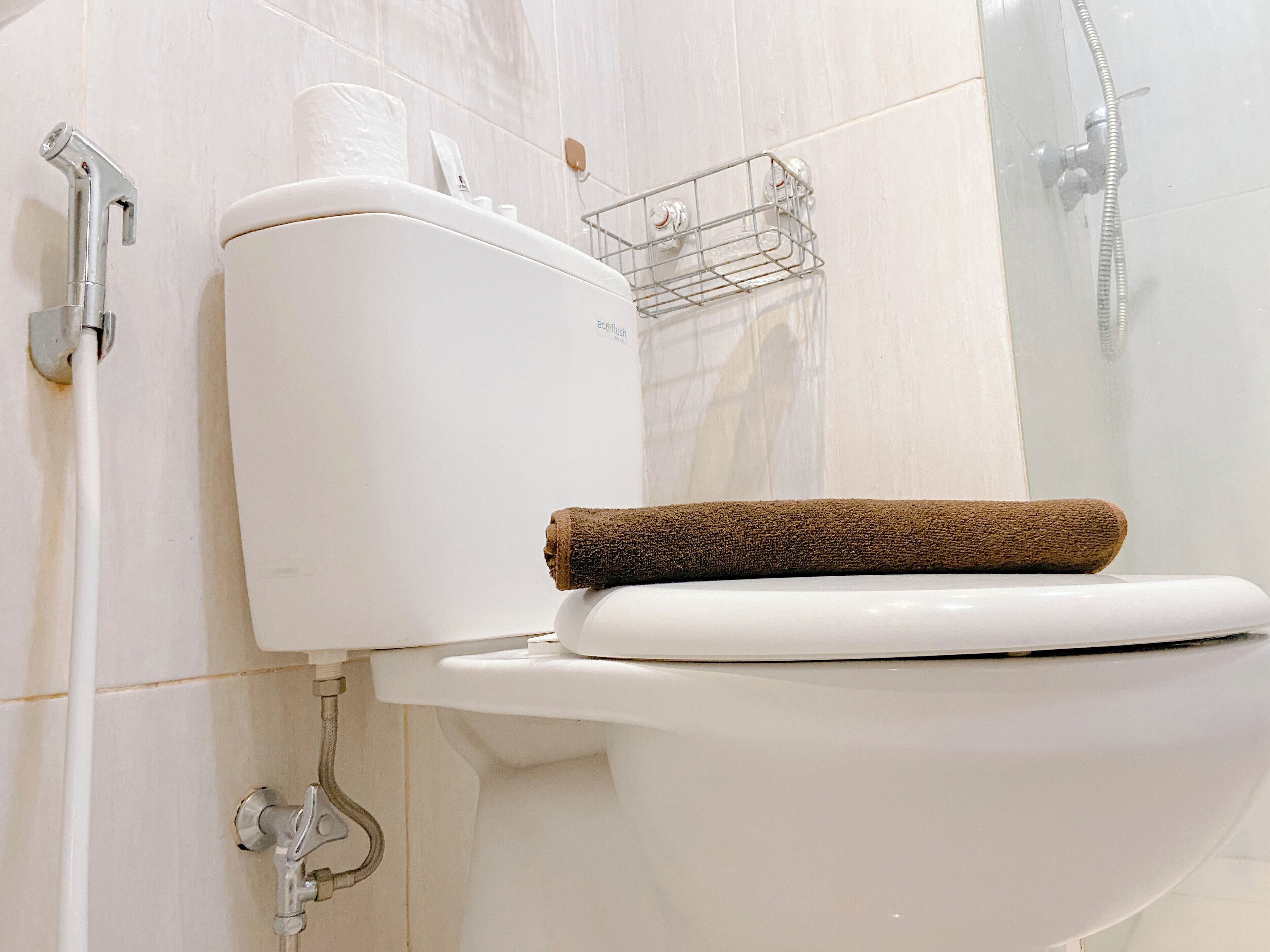 Un baño moderno con inodoro blanco, ducha y perchero para toallas.