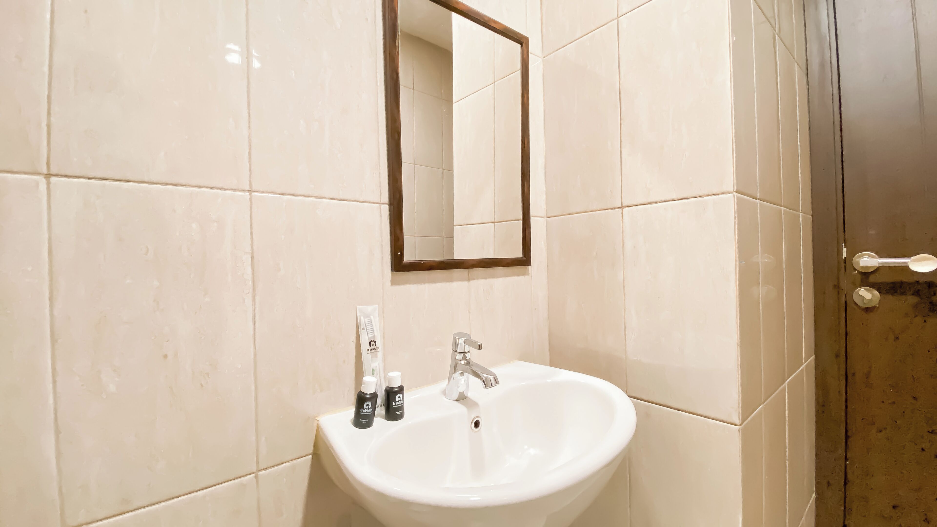 Une salle de bain avec un lavabo blanc, un miroir et des articles de toilette.