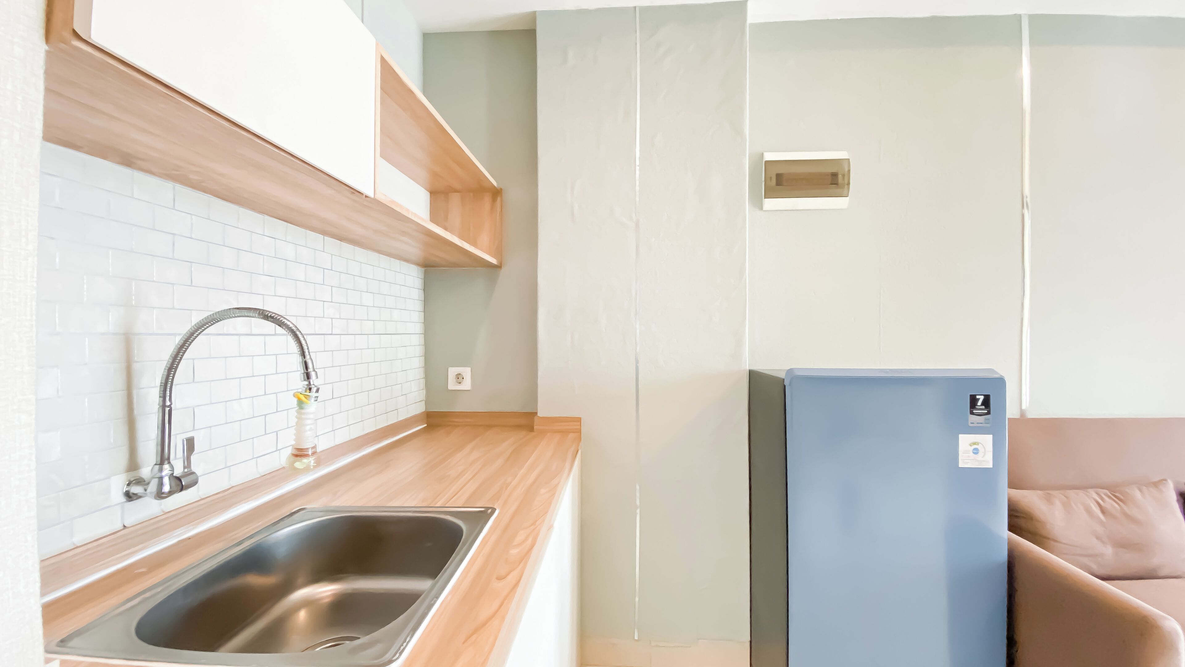 Una cocina compacta con un lavamanos de acero inoxidable, una encimera de madera y un refrigerador azul.