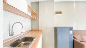 Une cuisine de taille réduite, dotée d’un évier en acier inoxydable, d’un plan de travail en bois et d’un réfrigérateur bleu.