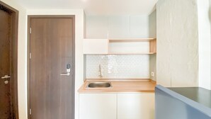 Une cuisine avec une porte en bois, un évier en acier inoxydable, des meubles de couleur claire et un dosseret carrelé.