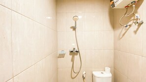 Bathroom features a shower with handheld showerhead and wall-mounted faucet, a toilet, and a small shelf with storage.