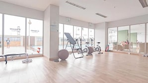 A spacious indoor gym with exercise equipment, large windows, and a clean, modern design.