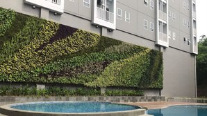 Un edificio moderno con un muro verde curato e un'area piscina circolare.