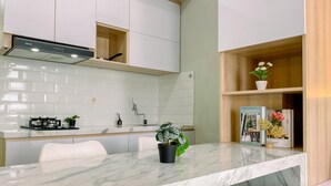 Una cucina moderna con mobili bianchi, un piano di lavoro in marmo e un piano cottura integrato.