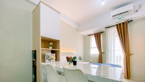 Una cucina moderna con un piano di lavoro in marmo, due sedie bianche, un dispenser d'acqua e uno scaffale con oggetti decorativi.