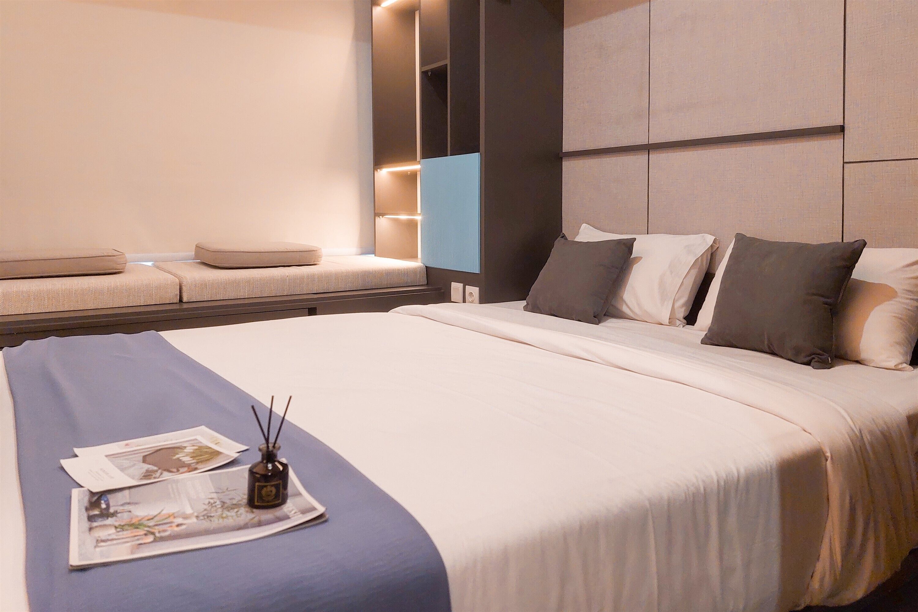 Een moderne hotelkamer met een groot bed, een zithoek met kussens en een wandlamp.