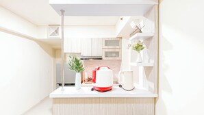 Een moderne keuken met witte kastjes, een wit aanrecht, een rode en witte koffiezetapparaat, een witte mok en een vaas met bloemen.