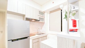Een moderne keuken met witte kastjes, een inbouwoven en een raam met een rode vaas.