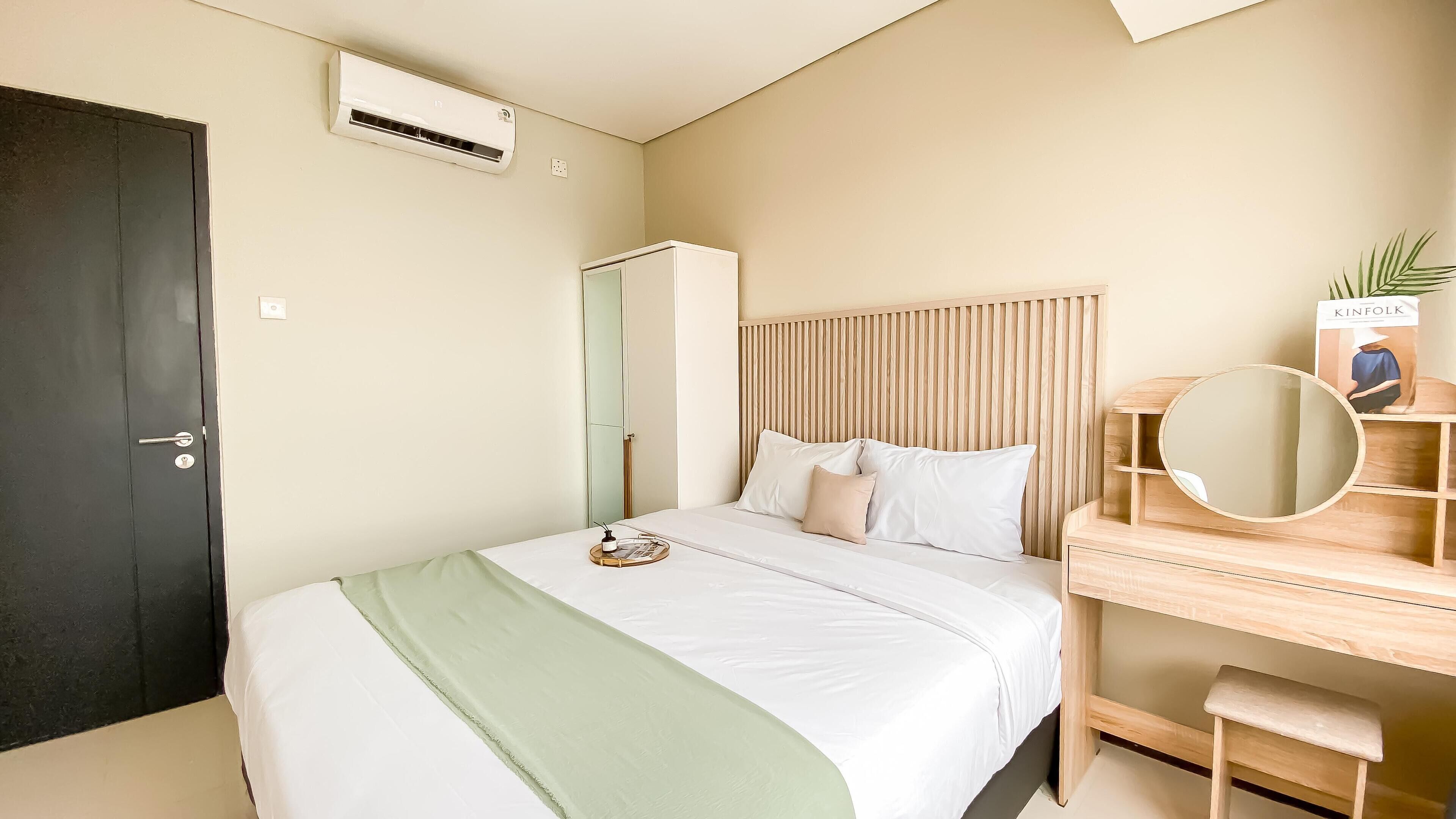 A bedroom with a bed, bedside table, mirror, and a wardrobe.