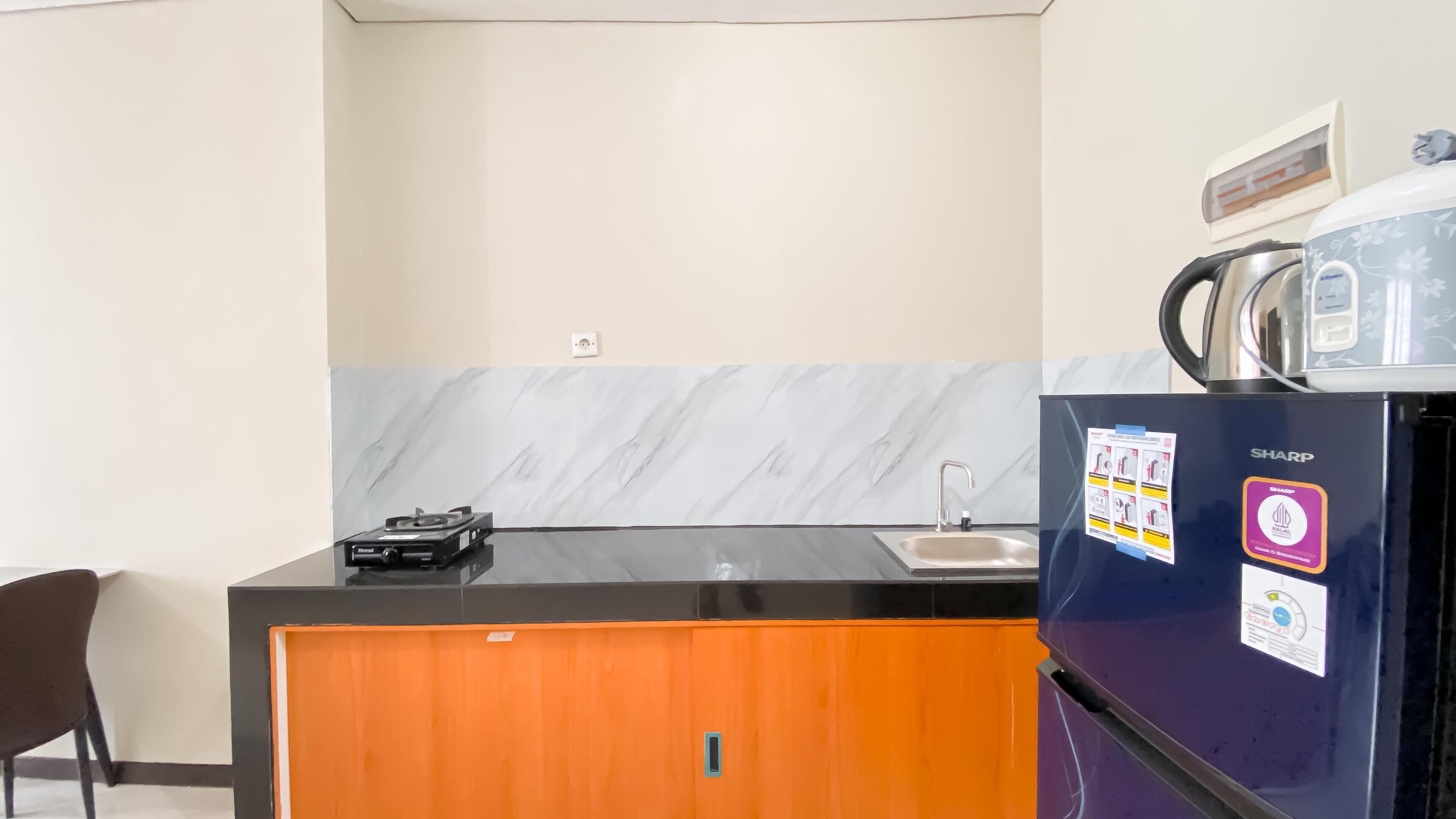 A compact kitchen with a marble backsplash, a black refrigerator, and a small sink.