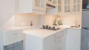 A modern kitchen with white cabinetry, a built-in gas stove, and a stainless steel refrigerator.