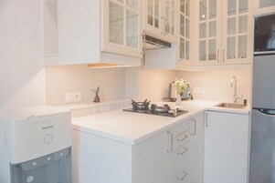 A modern kitchen with white cabinetry, a built-in gas stove, and a stainless steel refrigerator.