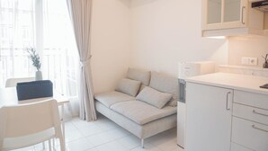 A modern, compact living space with a sofa, a dining table, and a kitchen area.