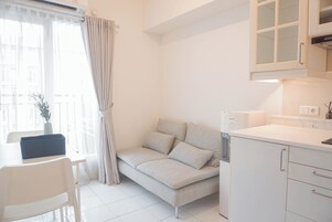 A modern, compact living space with a sofa, a dining table, and a kitchen area.
