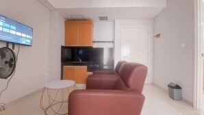 A compact living space with a kitchenette, a seating area, and a television mounted on the wall. - Nice and Comfy 2BR Apartment At Silkwood Residence (Tangerang)
