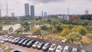 A parking lot with multiple cars, a body of water, and a cityscape with tall buildings in the background. - Nice and Comfy 2BR Apartment At Silkwood Residence (Tangerang)