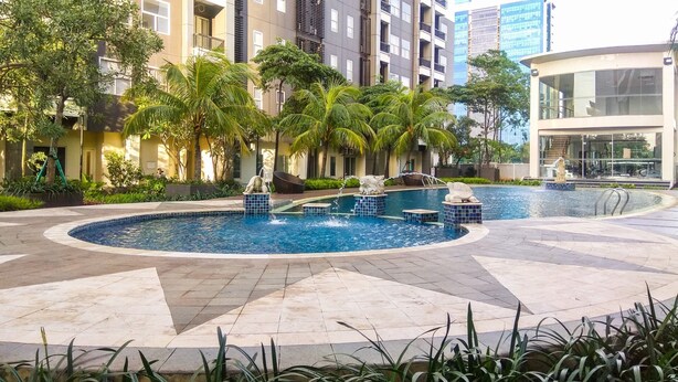 A swimming pool surrounded by palm trees and a modern building. - Nice and Comfy 2BR Apartment At Silkwood Residence (Tangerang)
