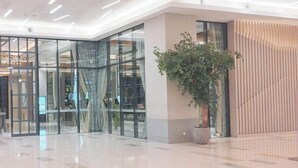A spacious lobby with a glass partition, a potted plant, and a modern design.