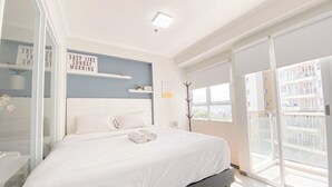 Un dormitorio moderno con una cama grande, una mesita de noche, un espejo y una ventana con vistas a la ciudad.
