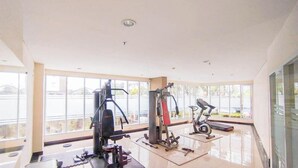 Un gimnasio con máquinas de cardio, equipo de levantamiento de pesas y un amplio ventanal con vistas al exterior.