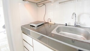 Una cocina moderna con un lavamanos de acero inoxidable, una campana extractora empotrada y una encimera con un electrodoméstico.