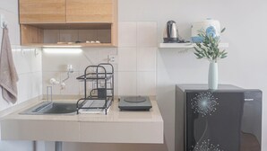 Cuina amb un rentaplat, una tetera, una cafetera i un vas decoratiu sobre una superfície.