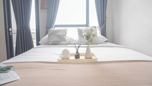 Un llit ben fet amb un cistell d'articles de tocador, un ram de flors i un coixí geomàtric.