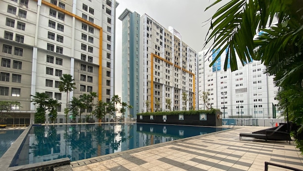 A swimming pool with tiled deck, surrounded by tall residential buildings. - Spacious and Homey Studio Room Paramount Skyline Apartment (Gading Serpong)