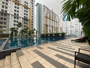 A swimming pool with tiled deck, surrounded by tall residential buildings. - Spacious and Homey Studio Room Paramount Skyline Apartment (Gading Serpong)
