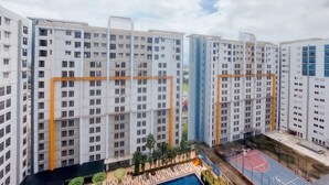 A high-rise residential building with multiple floors, balconies, and a basketball court. - Spacious and Homey Studio Room Paramount Skyline Apartment (Gading Serpong)