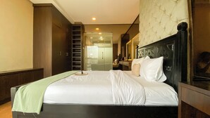 A hotel room with a bed, a desk, a chair, and a wardrobe. - Elegant and Spacious Studio at Kemang Mansion Apartment (Jakarta)
