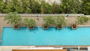 A swimming pool with tiled flooring, surrounded by wooden deck and potted plants. - Elegant and Spacious Studio at Kemang Mansion Apartment (Jakarta)