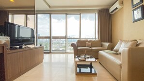 A spacious living room with a large flat-screen TV, a beige sofa, and a coffee table. - Elegant and Spacious Studio at Kemang Mansion Apartment (Jakarta)