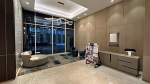 Een moderne hotel lobby met een glazen wand, een receptiebalie en een zithoek.