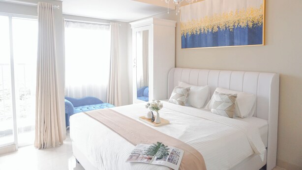 Une chambre à coucher avec un grand lit, un lustre, un tableau et une vue sur l’extérieur.