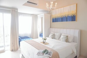 Een slaapkamer met een groot bed, een kroonluchter, een schilderij en uitzicht op het omliggende landschap.
