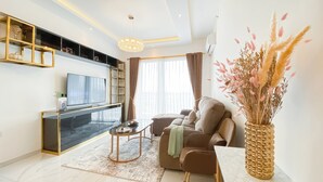 Un salon moderne avec un téléviseur à écran plat, un canapé, une table basse et un vase décoratif.