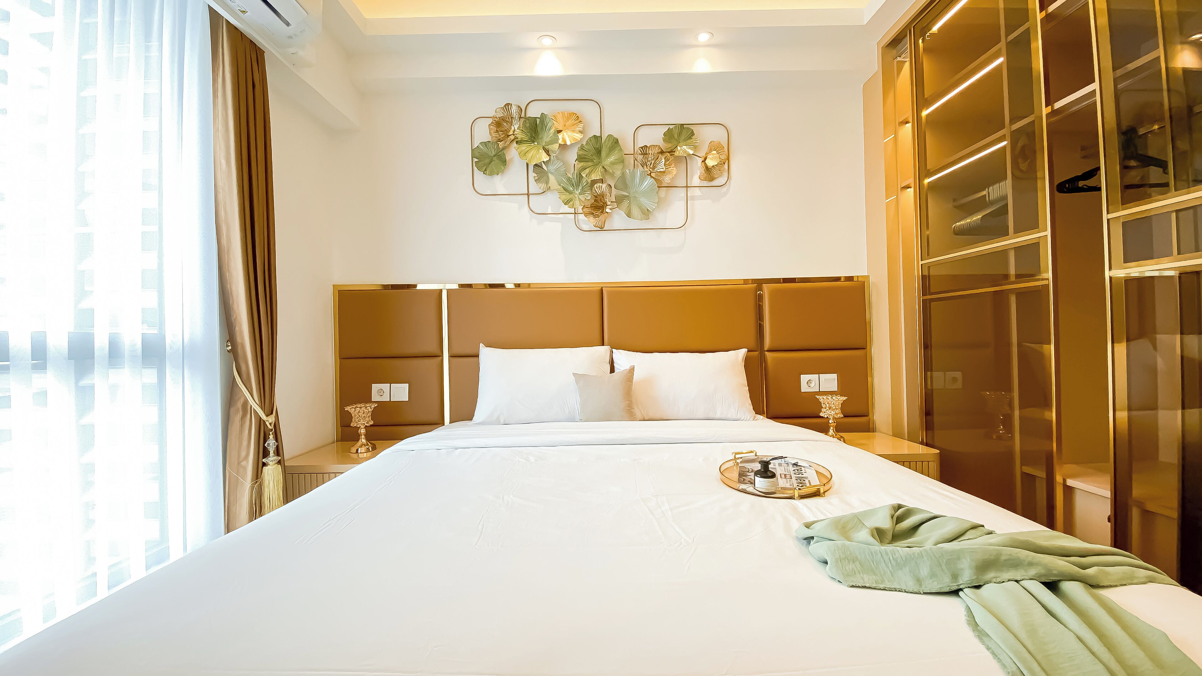 Une chambre d’hôtel dotée d’un grand lit, d’une tête de lit au motif géométrique, d’une armoire aux portes en verre et d’un élément décoratif fixé au mur.