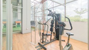 A gym with exercise equipment, a wooden floor, and a large window with a view of trees.